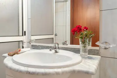 a bathroom sink with a vase of red roses at Apartment lucy in Arco da Calheta