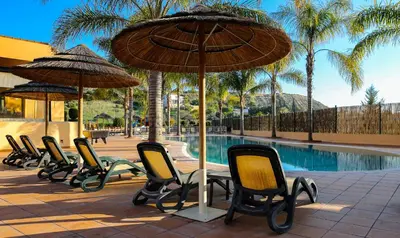 a row of chairs and umbrellas next to a pool at LuzBay Pool Apartments in Luz