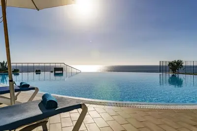 a large swimming pool with an umbrella and a chair at Formosa Infinity Pool Apartment in Funchal