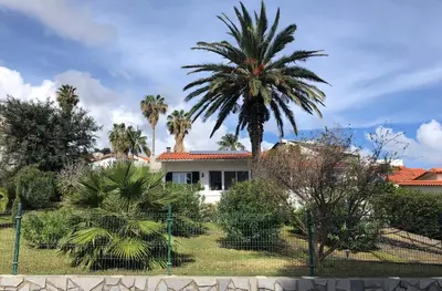 a house with palm trees in front of it at Casa Palmeira - Ferienhaus mit Meerblick in Caniço