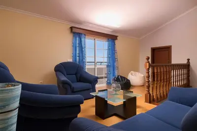 a living room with blue chairs and a table at Villa Neto in Calheta