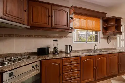 a kitchen with wooden cabinets and a counter top at Villa Neto in Calheta