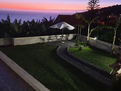 a garden with an umbrella and a table and chairs at Villa Neto in Calheta