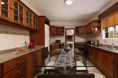 a kitchen with wooden cabinets and a table with chairs at Villa Neto in Calheta