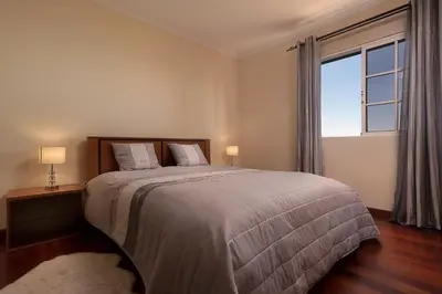 a bedroom with a large bed and a large window at Villa Neto in Calheta