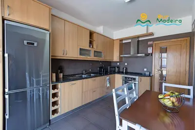 a kitchen with wooden cabinets and a table and a refrigerator at OurMadeira - Casa da Belita in Calheta