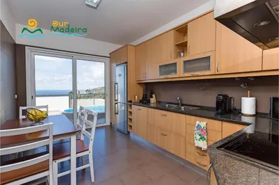 a kitchen with a table and a view of the ocean at OurMadeira - Casa da Belita in Calheta