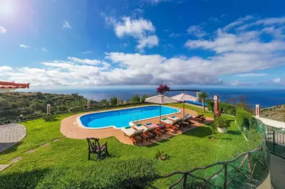 a swimming pool with lounge chairs and an umbrella at OurMadeira - Theo's House in Calheta