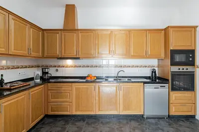 a kitchen with wooden cabinets and a white dishwasher at OurMadeira - Theo's House in Calheta