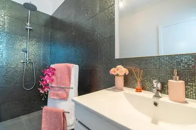 a bathroom with a sink and a shower with a mirror at Casa das Abertas in Calheta