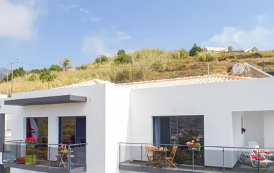 a white house with a balcony with tables and chairs at Casa das Abertas in Calheta