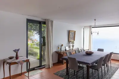 a dining room with a long table and a large window at Casa da Manta in Fajã da Ovelha