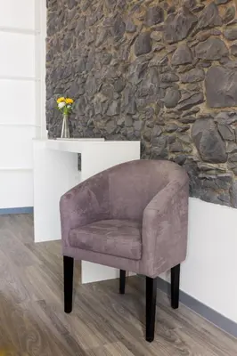 a brown chair sitting in front of a stone wall at Apartamentos Funchal by Petit Hotels in Funchal