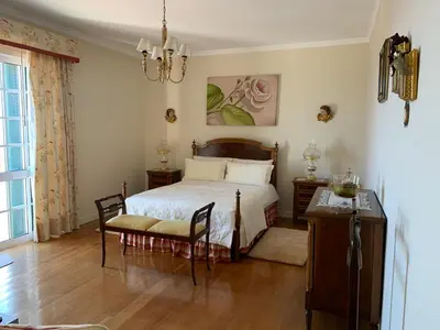 a bedroom with a bed and a chair and a table at Vila Tagus Garajau in Caniço