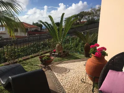 a patio with chairs and potted plants in a yard at Vila Tagus Garajau in Caniço