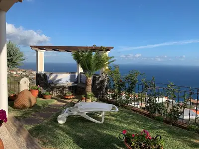 a garden with a white bench on the grass at Vila Tagus Garajau in Caniço
