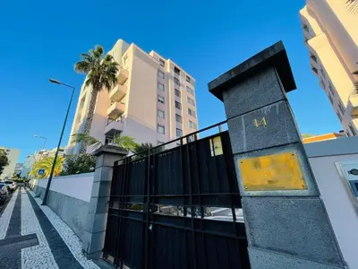 a fence in front of a building with a palm tree at Apto Barreiro by Susy's Holidays in Funchal