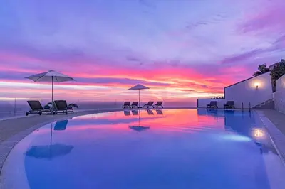 a pool with chairs and umbrellas and a sunset at Sky Villa by An Island Apart in Funchal