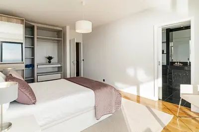 a white bedroom with a large bed and a table at Sky Villa by An Island Apart in Funchal