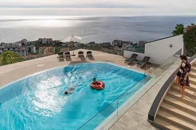 a woman standing next to a swimming pool with a person in a raft at Sky Villa by An Island Apart in Funchal