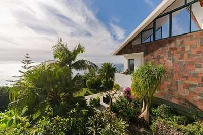 a brick house with palm trees and plants at Sky Villa by An Island Apart in Funchal