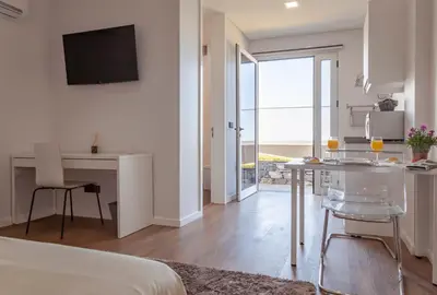 a room with a bed and a kitchen with a table at Infinito Azul in Caniço