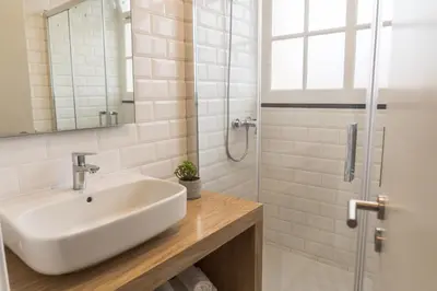 a white bathroom with a sink and a shower at Funchal Village Studios in Funchal