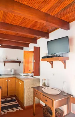 a kitchen with wooden cabinets and a tv on the wall at Casa da Manta - Palheiro in Fajã da Ovelha