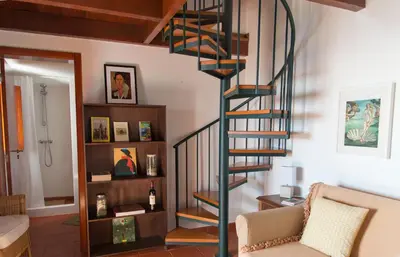 a spiral staircase in a living room with a couch at Casa da Manta - Palheiro in Fajã da Ovelha