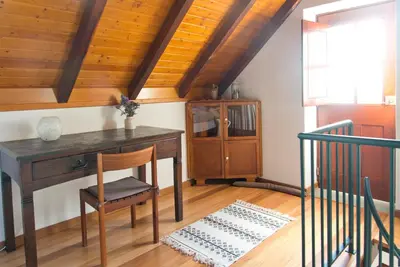 a desk and chair in a room with a wooden ceiling at Casa da Manta - Palheiro in Fajã da Ovelha