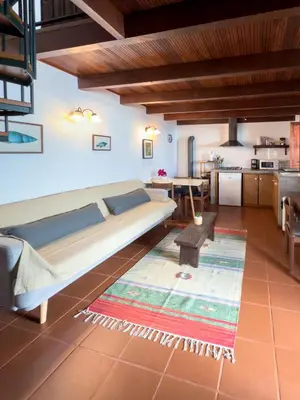 a living room with a bed and a kitchen at Casa da Manta - Palheiro in Fajã da Ovelha