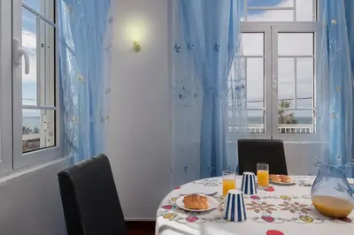 a dining room with a table with food and two windows at CAPTAIN´S HOUSE in Paul do Mar