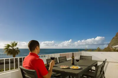 a man sitting at a table with a glass of wine at CAPTAIN´S HOUSE in Paul do Mar