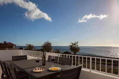 a table on a balcony with a view of the ocean at CAPTAIN´S HOUSE in Paul do Mar