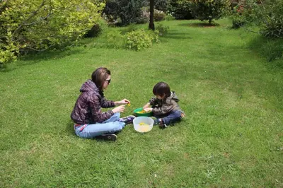a woman and a child sitting in the grass at Bio Quinta do Pantano, Agro Turismo in Santo da Serra