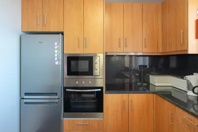a kitchen with stainless steel appliances and wooden cabinets at Apartment Laranjeiras in Calheta