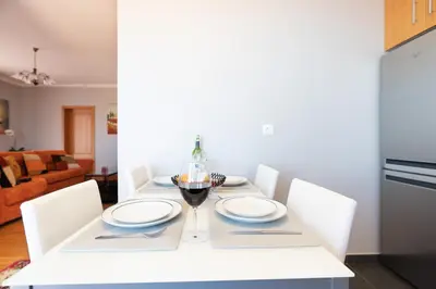 a white table with white plates and a glass of wine at Apartment Laranjeiras in Calheta