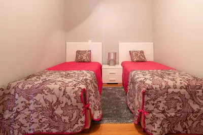 two beds in a small room with red sheets at Apartment Laranjeiras in Calheta
