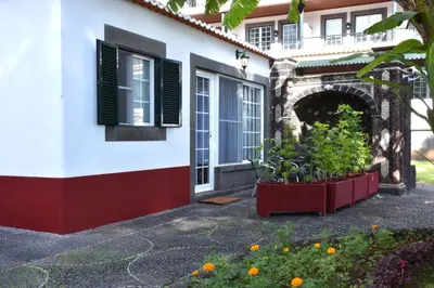 a building with two windows and a courtyard with flowers at Quinta Da Penha De Franca in Funchal