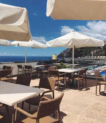 an outdoor patio with tables and chairs and umbrellas at Quinta Da Penha De Franca in Funchal