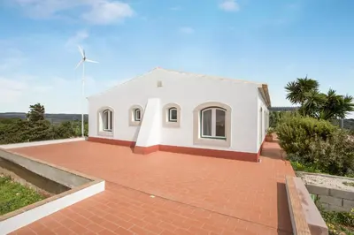 a white house on top of a grassy hill at Casa das Furnas - Eco Home in Vila do Bispo