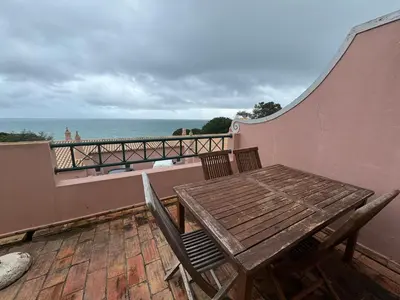 a wooden table and chairs on a balcony with the ocean at Dream Executive Apartments in Luz
