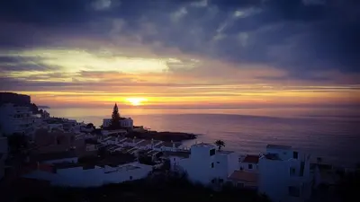 a sunset over a city with white buildings and the ocean at Luz Beach Ocean Front Apartment in Luz