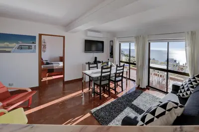 a living room with a couch and a table with chairs at Luz Beach Ocean Front Apartment in Luz