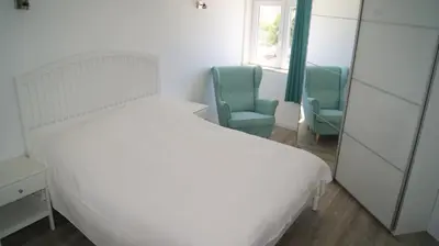 a bedroom with a white bed and two blue chairs at Apartamento Próximo da Praia in Luz