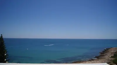 a view of the ocean with a boat in the water at Apartamento Próximo da Praia in Luz