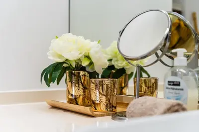 a mirror and a vase of white flowers on a bathroom counter at Golden escape in Funchal in Funchal