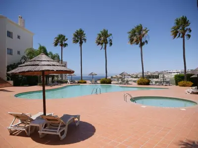 a swimming pool with two lounge chairs and an umbrella at Large Penthouse Near Porto de Mos Beach With Magnificent Views In Lagos in Lagos