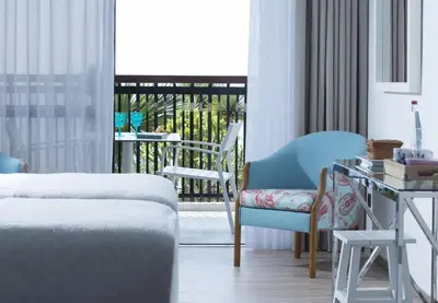 a room with a bed and a chair and a balcony at Hotel Baia Azul in Funchal