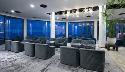 a waiting room with chairs and tables and windows at Hotel Baia Azul in Funchal